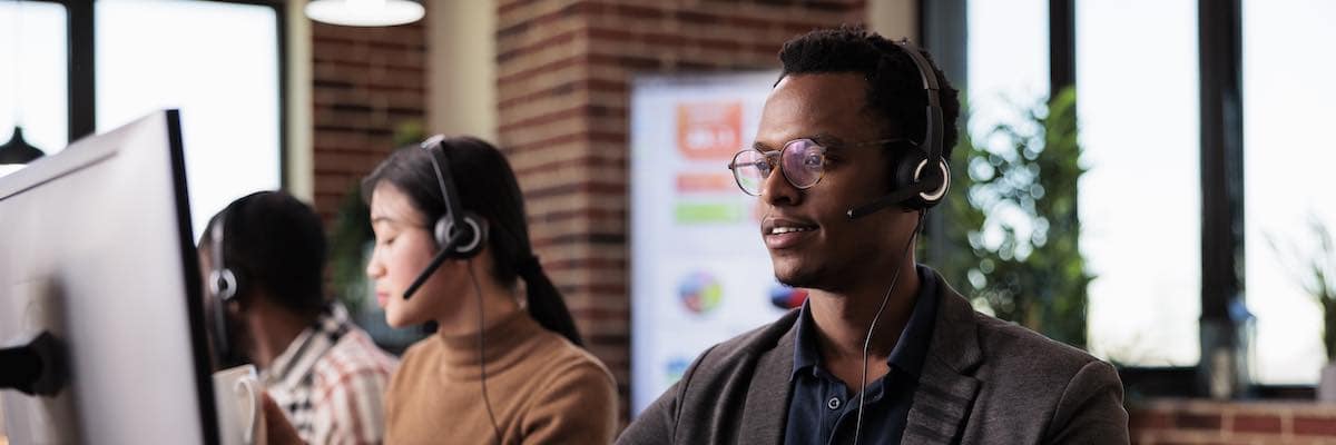 African american helpline employee working at call center reception with multiple monitors