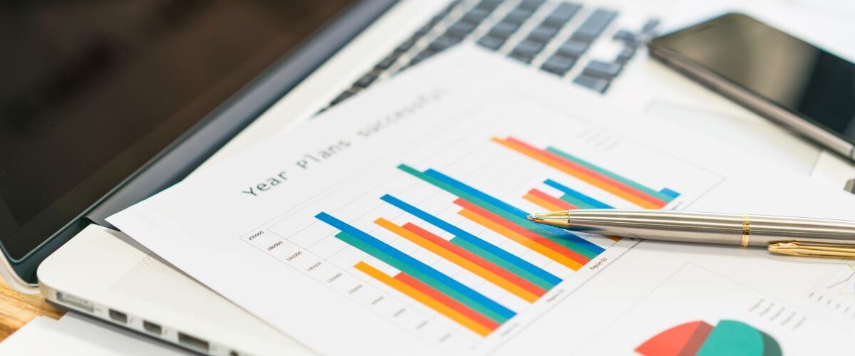 A close-up of a bar chart on a piece of paper. The paper has a pen on it and is on a laptop.