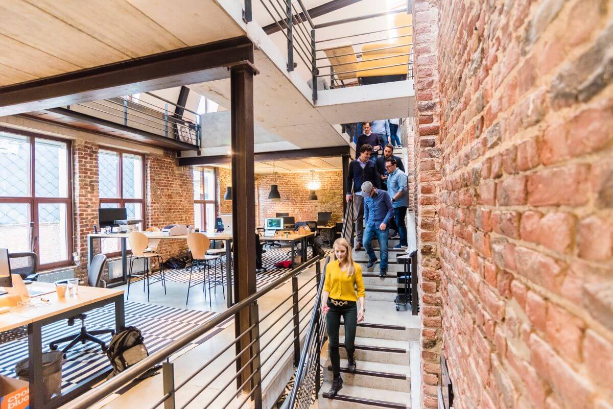 A woman walking down stairs in an office space with a group of people behind her.