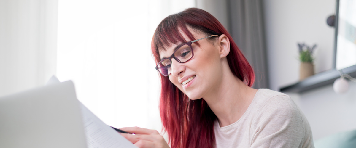 Happy woman at home using laptop and checking bills and invoice document