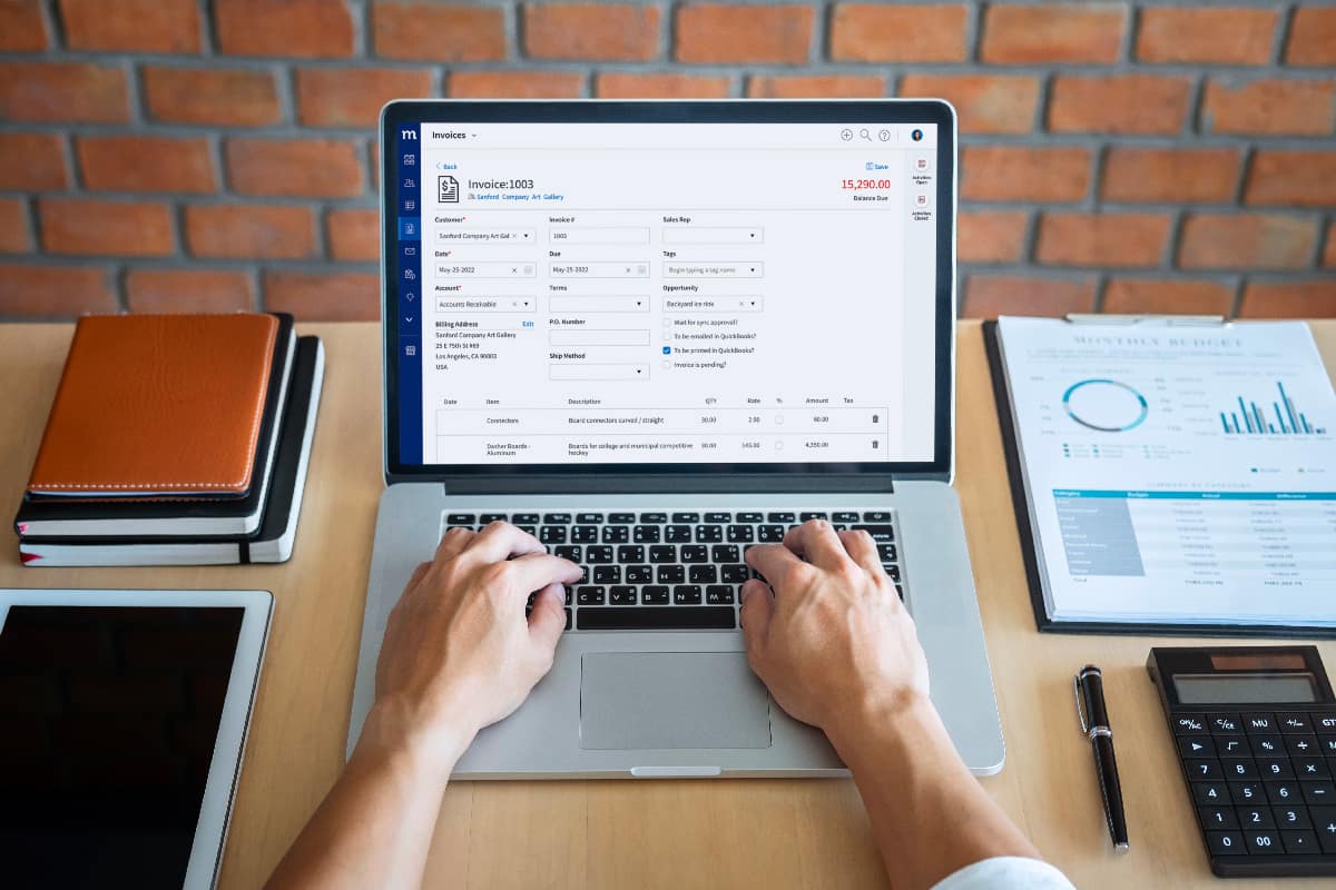 top-view of person typing on laptop with the screen showing a Method QuickBooks desktop invoice