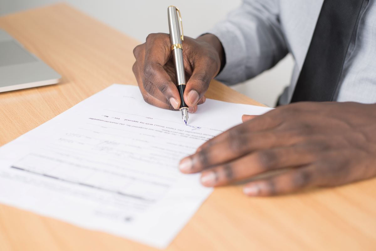 A closeup of a man signing a document.