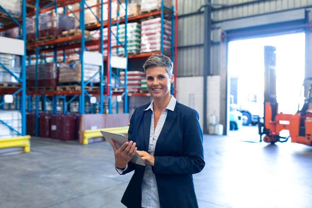 senior woman holding a tablet and smiling in a warehouse