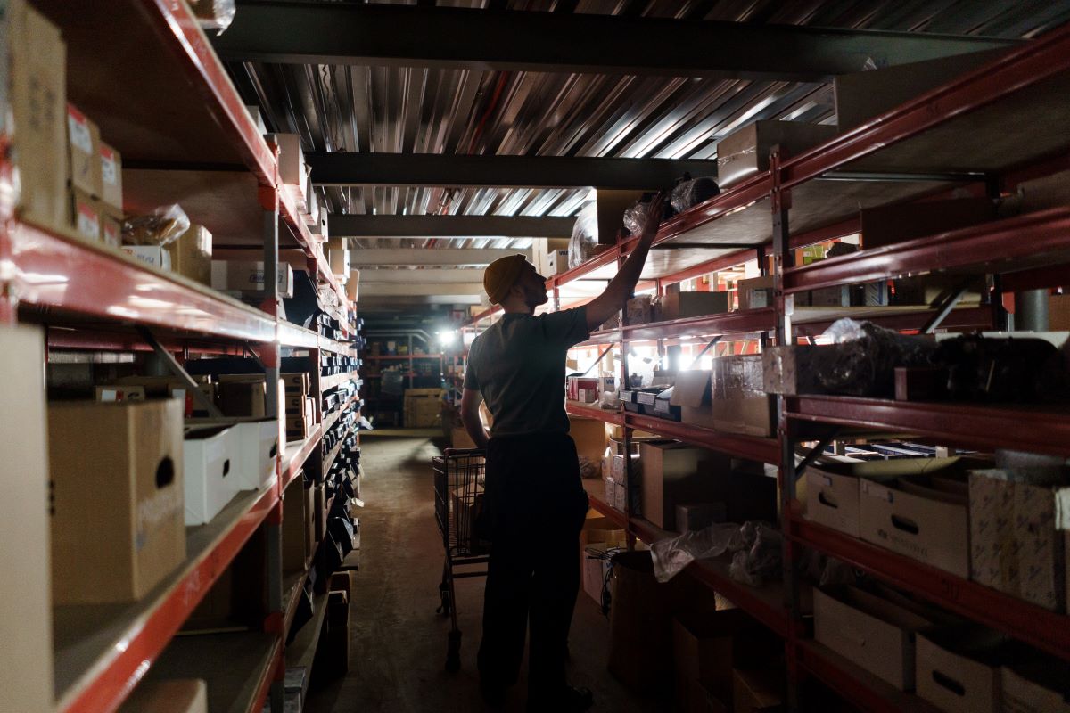 A man in a dimly lit warehouse looking at inventory on a shelf.