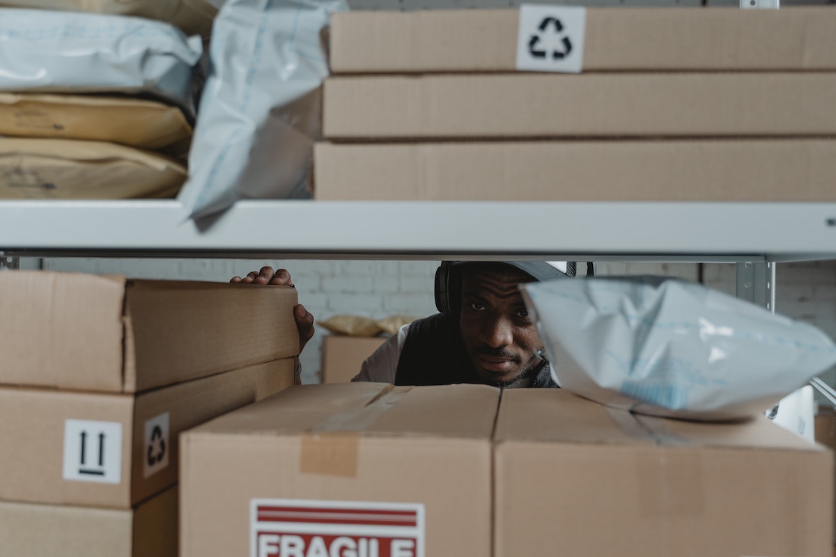 A man peering through a shelf full of boxes.