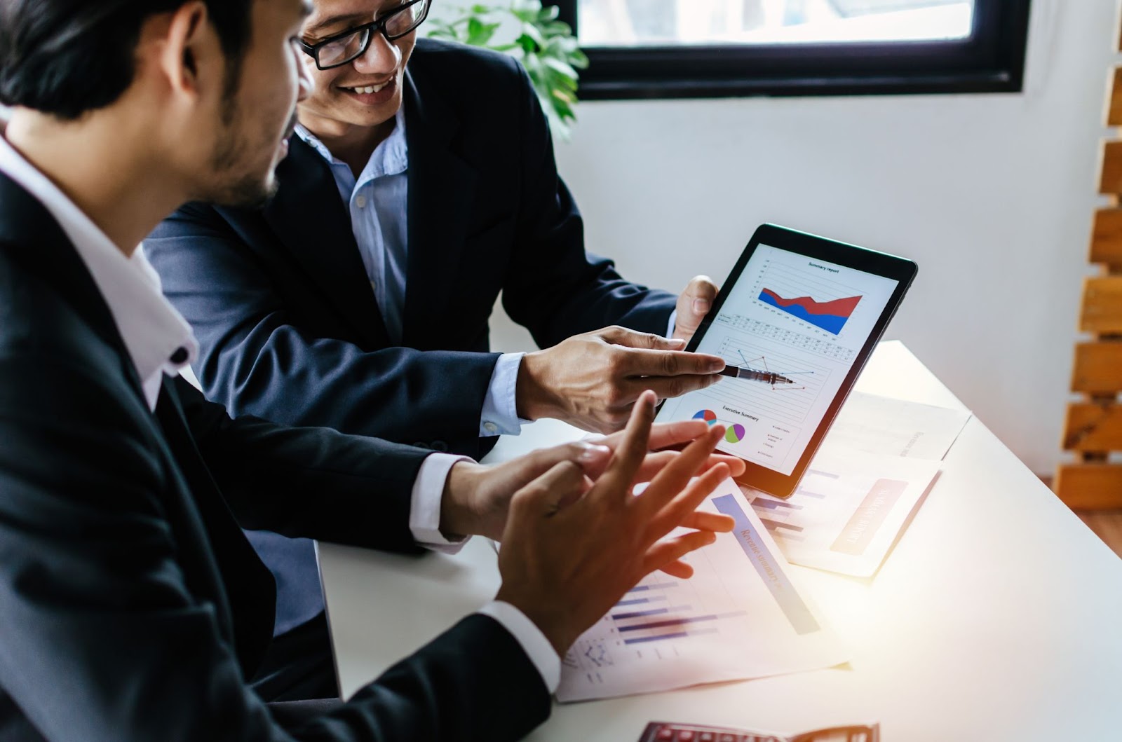 Businessmen looking at graphs on a tablet