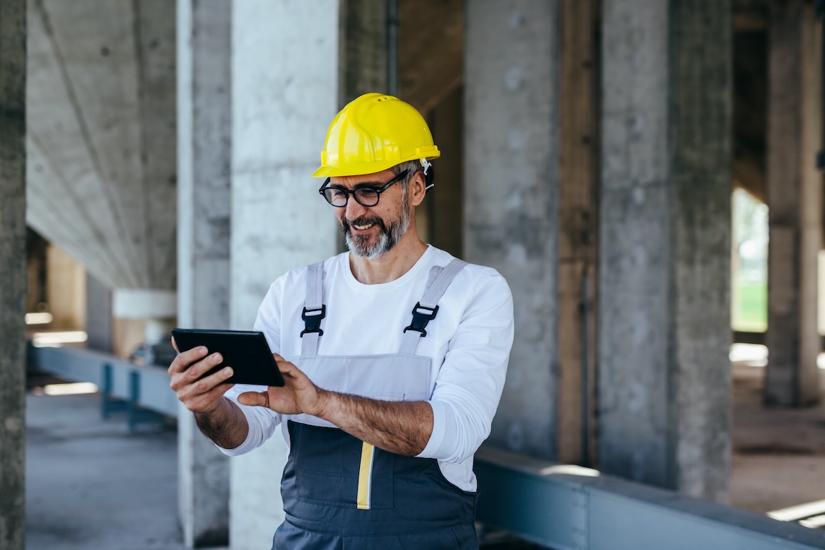 Man in construction helmet working on tablet at construction site