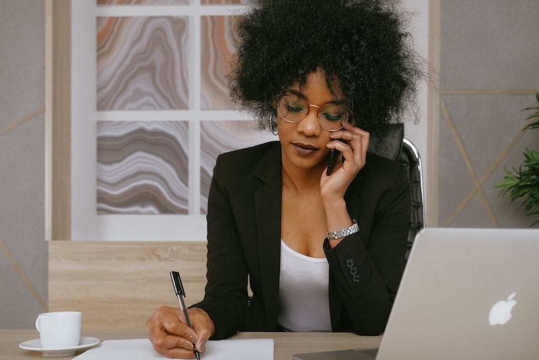 Woman speaking on cellphone at desk with computer