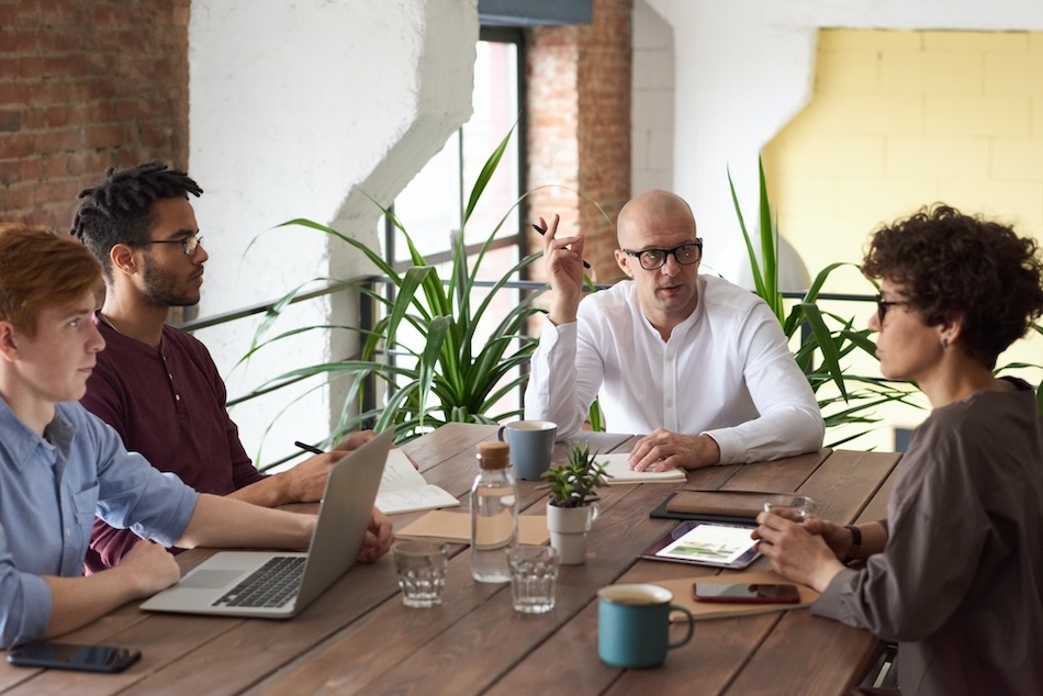 Businesspeople conversing at a table with computers