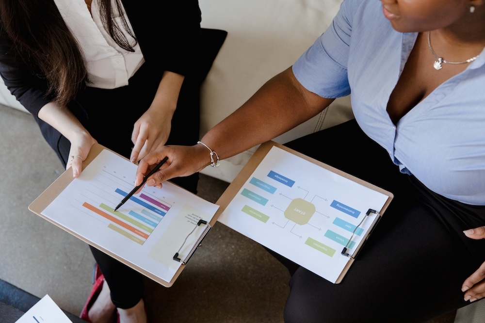 Two women discuss data charts.