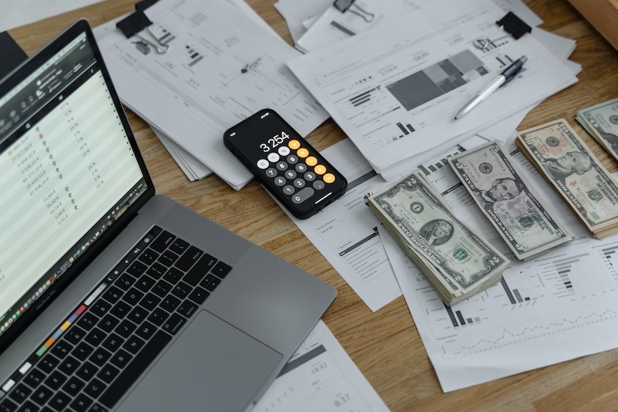 A computer, a cellphone, and cash on a desk