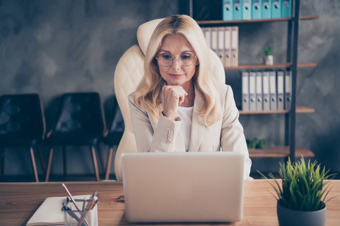 Photo of freelancer business, woman pondering on searching of way of development of her corporation sitting before laptop using internet