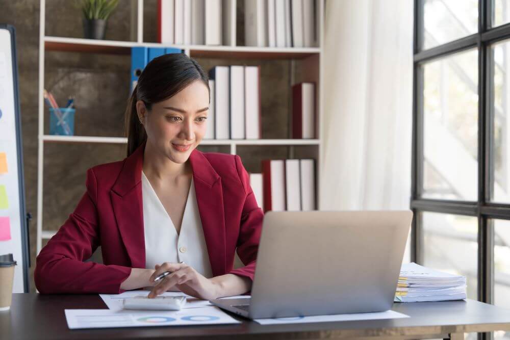 Young woman looking at a laptop and smiling in an office