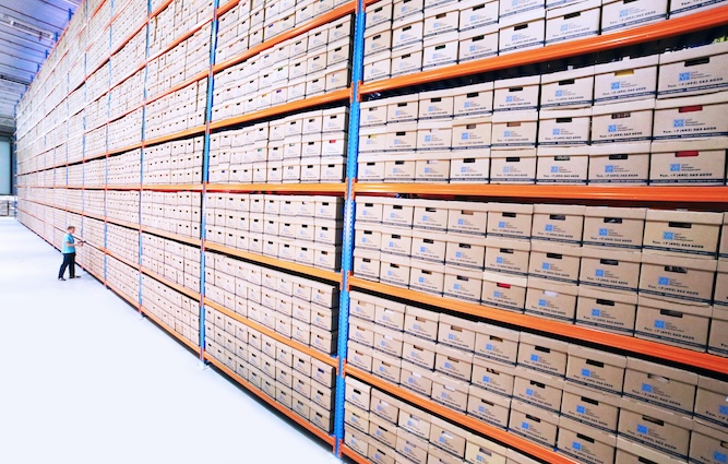 Man with RFID scanner registering boxes in warehouse.