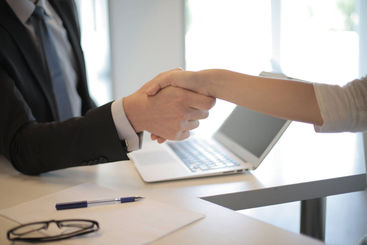 Two business people shaking hands over an office desk.