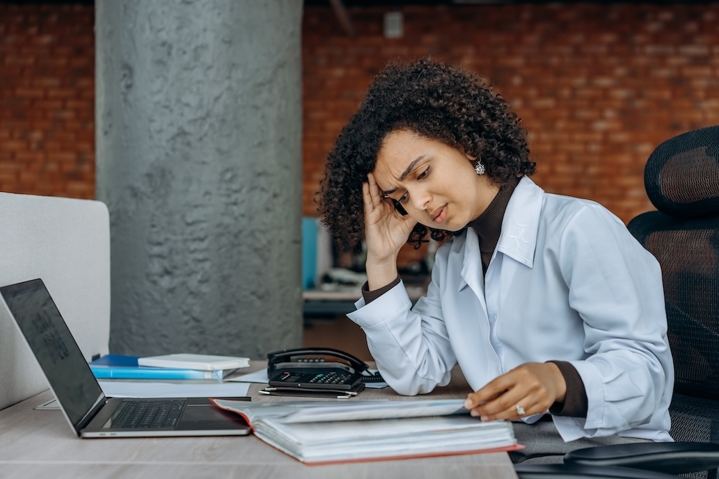 Woman with irritated expression studies documents on desk