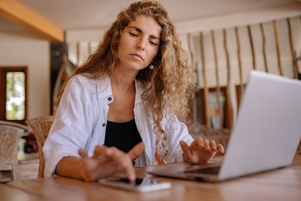 woman in white blazer using macbook pro