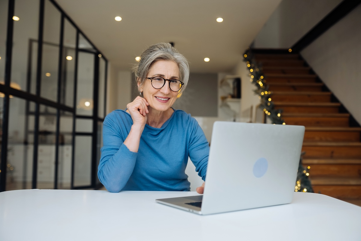 Happy mature middle aged elderly woman reading good news looking at laptop