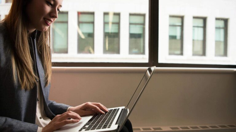 A woman on her laptop smiling.