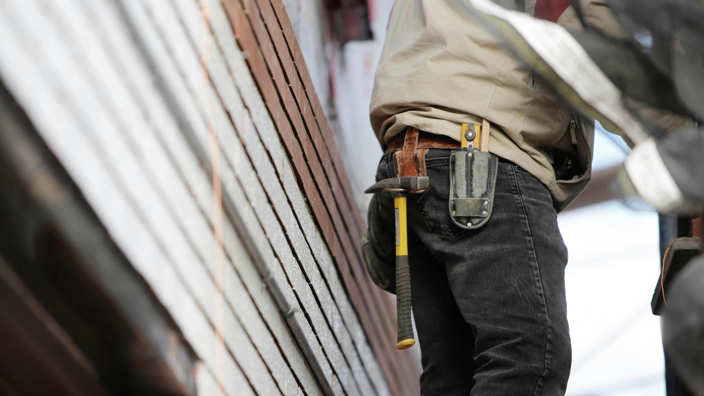 A photo of a contractor's work belt, with a hammer and X-acto knife visible.